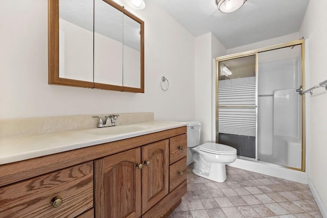 bathroom with vanity, baseboards, toilet, and a stall shower