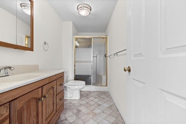 bathroom featuring vanity, toilet, baseboards, and a stall shower