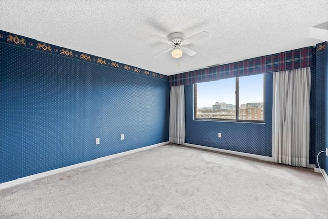 empty room featuring a ceiling fan, a textured ceiling, baseboards, and carpet