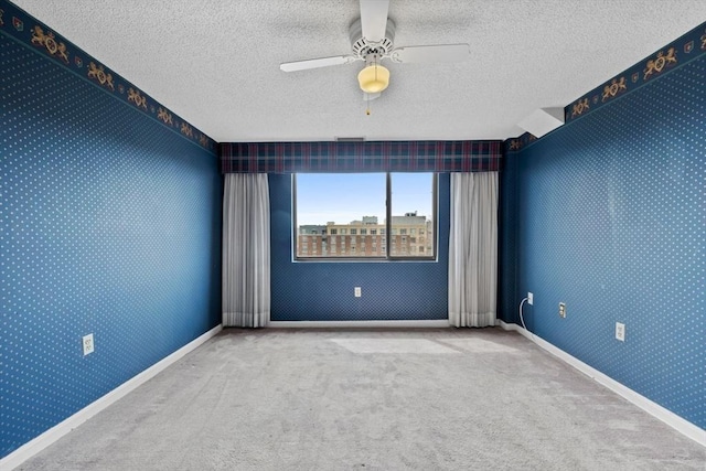 carpeted spare room with a textured ceiling, baseboards, and a ceiling fan