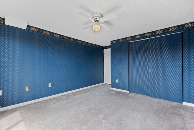 spare room featuring a textured ceiling, baseboards, ceiling fan, and carpet