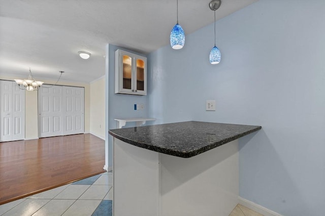 kitchen featuring a notable chandelier, baseboards, hanging light fixtures, light tile patterned flooring, and a peninsula
