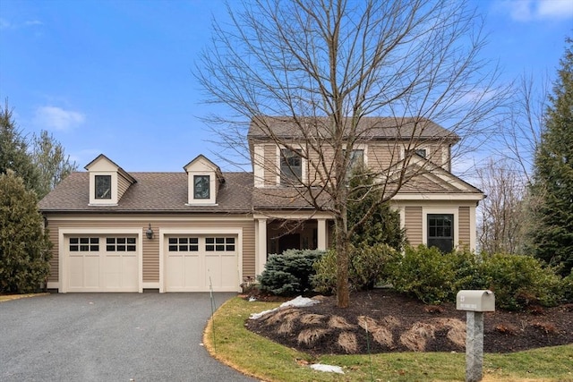 view of front of house featuring driveway, roof with shingles, and an attached garage