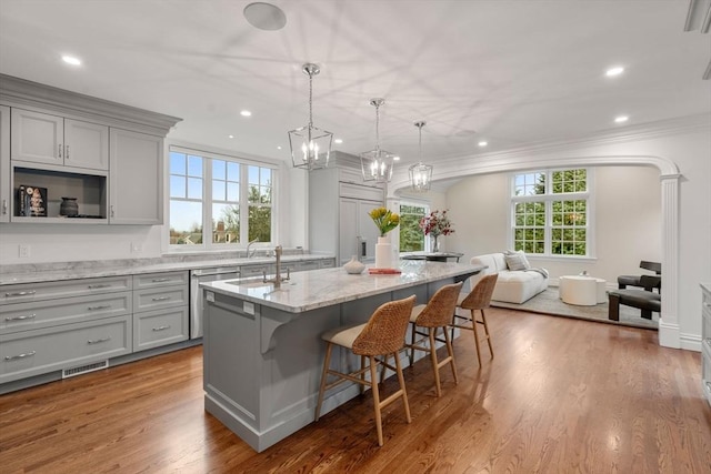 kitchen featuring light stone counters, gray cabinetry, visible vents, open floor plan, and an island with sink