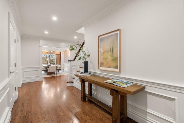 hallway featuring crown molding, recessed lighting, a decorative wall, stairway, and wood finished floors