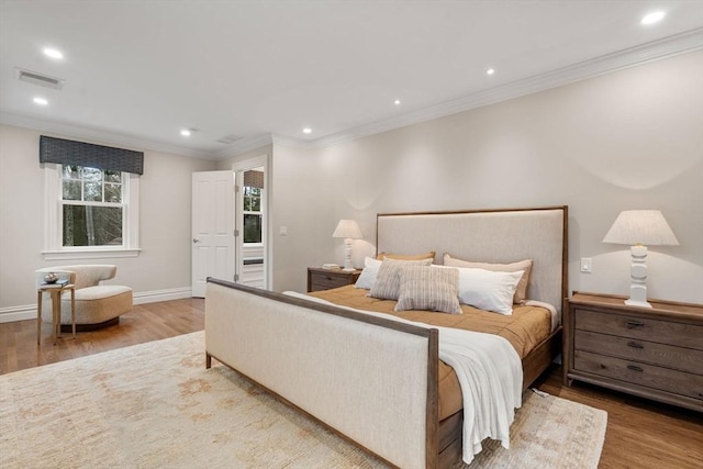 bedroom with baseboards, visible vents, ornamental molding, wood finished floors, and recessed lighting