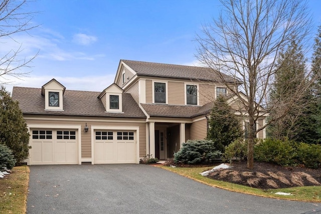 view of front facade featuring a garage, driveway, and a shingled roof