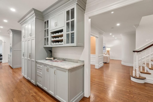 bar with light wood finished floors, recessed lighting, ornamental molding, baseboards, and stairs