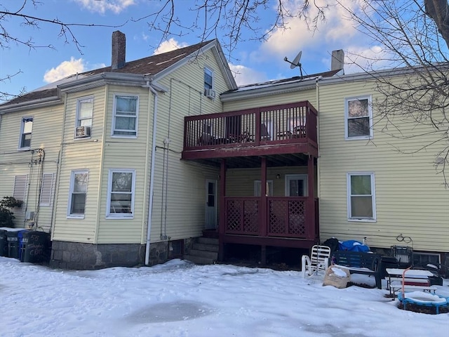 snow covered house featuring a chimney and a balcony