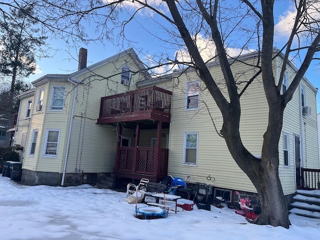 snow covered rear of property featuring a chimney