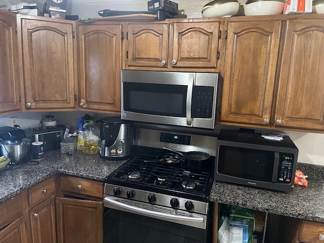 kitchen with appliances with stainless steel finishes, dark countertops, and brown cabinets