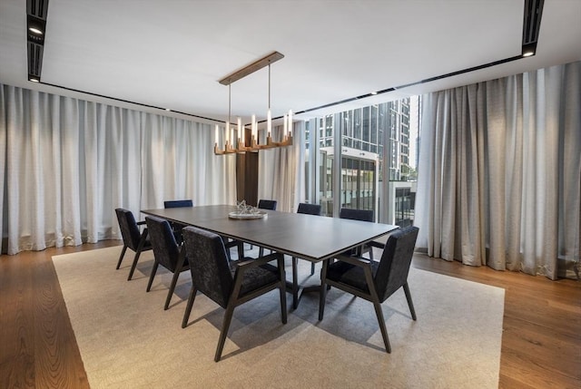 dining area with an inviting chandelier, a wall of windows, and light wood-type flooring