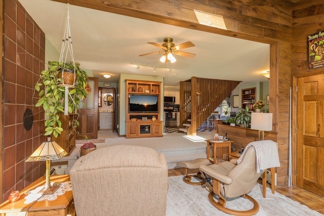 carpeted living room featuring wooden walls and ceiling fan