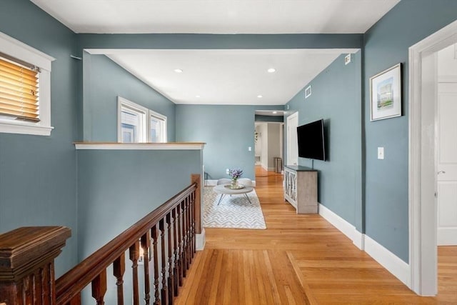 hallway featuring baseboards, visible vents, recessed lighting, light wood-style floors, and an upstairs landing