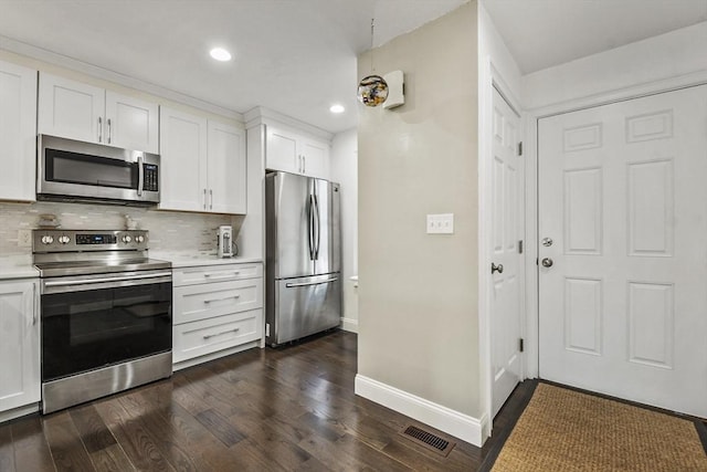 kitchen featuring stainless steel appliances, white cabinetry, dark hardwood / wood-style floors, and tasteful backsplash