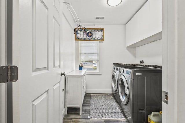 washroom featuring dark hardwood / wood-style flooring, separate washer and dryer, and cabinets