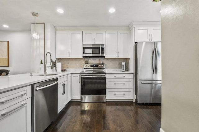 kitchen with appliances with stainless steel finishes, dark hardwood / wood-style flooring, white cabinets, decorative light fixtures, and sink