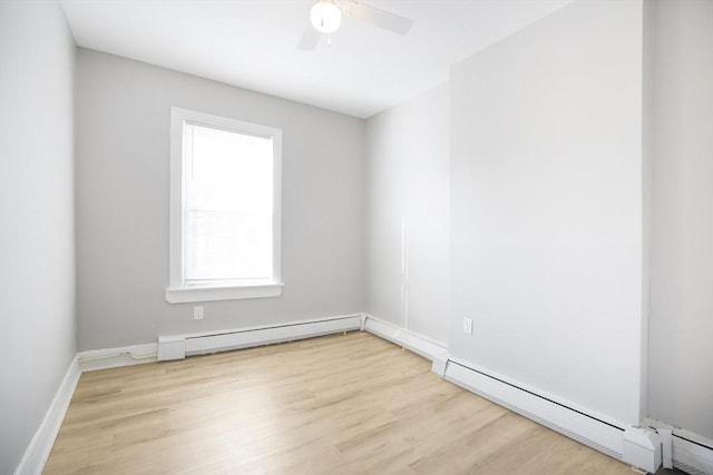 spare room featuring light wood finished floors, a baseboard heating unit, ceiling fan, and baseboards