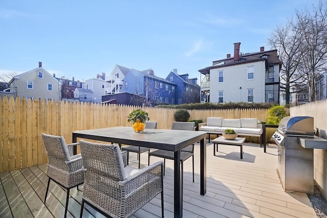 wooden terrace featuring a residential view, an outdoor living space, a fenced backyard, grilling area, and outdoor dining area