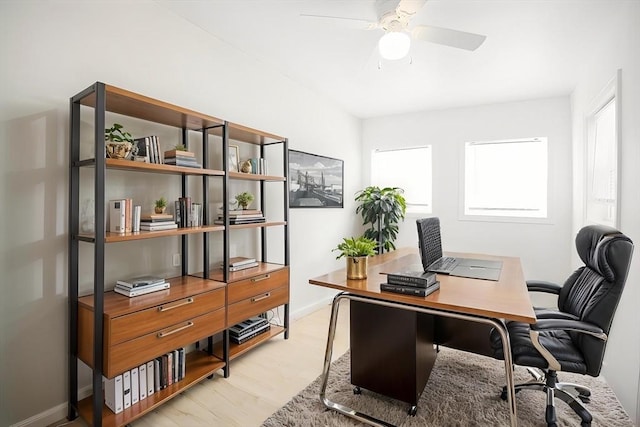 office area with light wood-style floors, ceiling fan, and baseboards