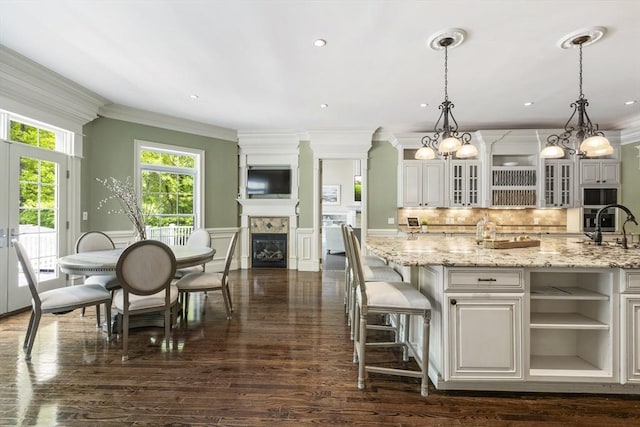 3 Newton Ln, Medway, MA 02053 - kitchen featuring crown molding, light stone countertops, dark wood-style flooring, a glass covered fireplace, and tasteful backsplash