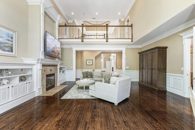 3 Newton Ln, Medway, MA 02053 - living area featuring ornate columns, a tiled fireplace, a decorative wall, dark wood-type flooring, and a high ceiling