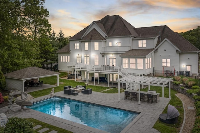 3 Newton Ln, Medway, MA 02053 - back of property at dusk with an outdoor living space, a shingled roof, a patio area, an outdoor pool, and a balcony