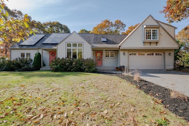 view of front of home with a garage, a front yard, and solar panels