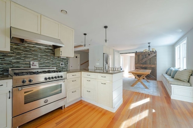 kitchen with range hood, high end range, hanging light fixtures, kitchen peninsula, and a barn door