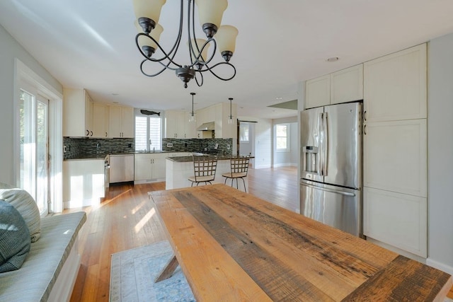 kitchen featuring stainless steel appliances, white cabinetry, pendant lighting, and backsplash