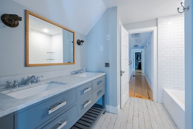 bathroom featuring hardwood / wood-style flooring, lofted ceiling, vanity, and shower / bathing tub combination