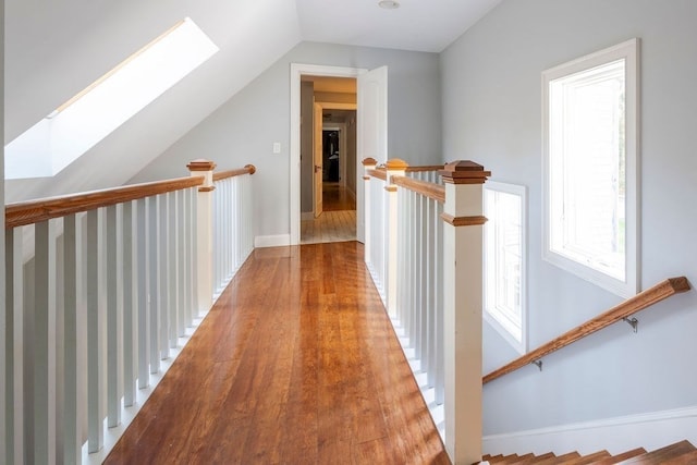 corridor with lofted ceiling with skylight and hardwood / wood-style floors