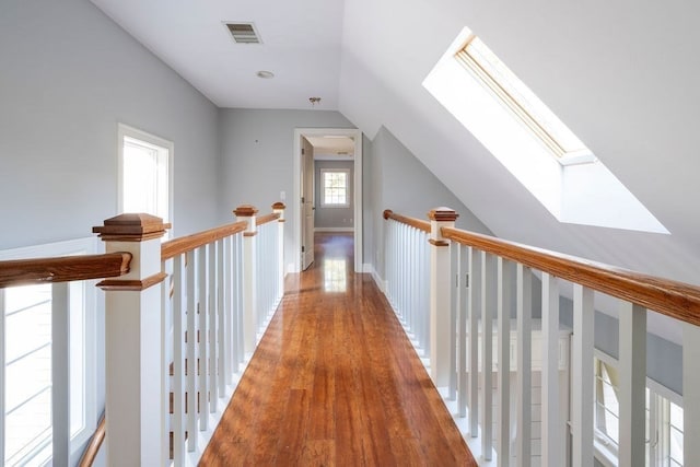 hallway with lofted ceiling with skylight and light hardwood / wood-style flooring