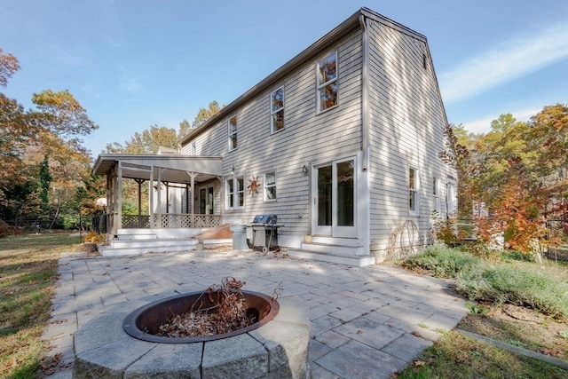 back of house with an outdoor fire pit and a patio