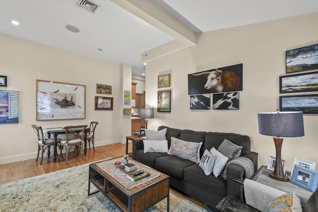 living room with baseboards, visible vents, and wood finished floors