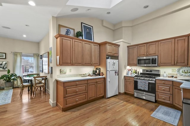 kitchen featuring light wood finished floors, brown cabinets, light countertops, and appliances with stainless steel finishes