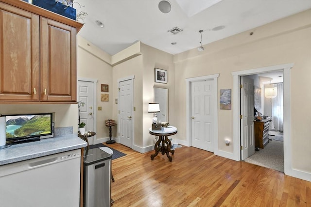 kitchen with baseboards, light wood finished floors, visible vents, and dishwasher