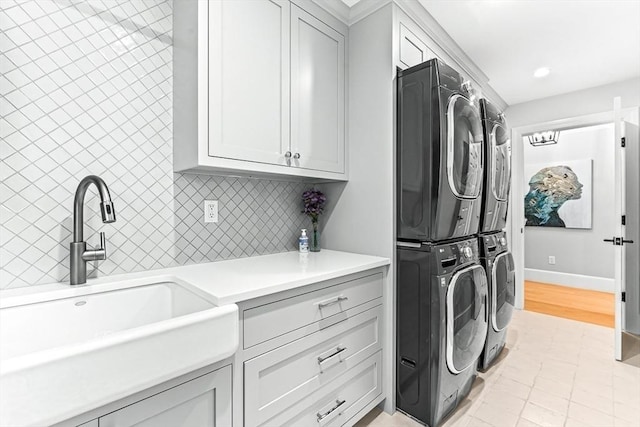 laundry room with cabinets, stacked washer and clothes dryer, and sink