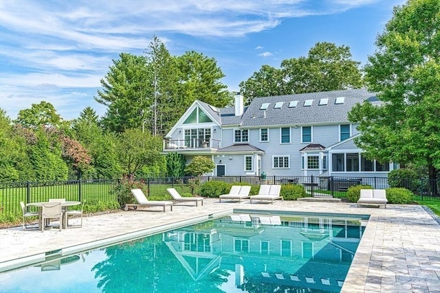 rear view of house featuring a fenced in pool and a patio