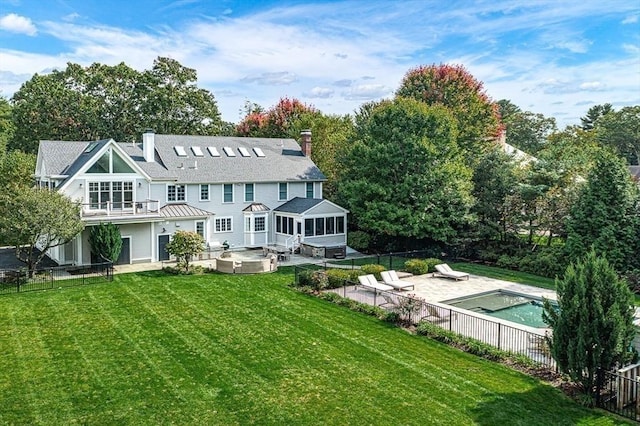 back of house featuring a lawn, a patio area, a sunroom, a pool with hot tub, and a balcony