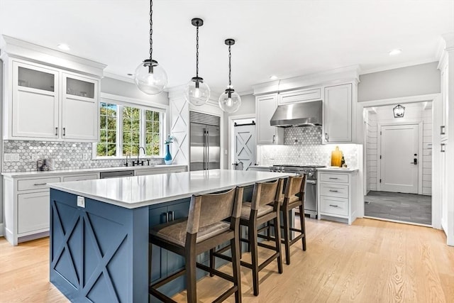 kitchen with a breakfast bar, hanging light fixtures, high quality appliances, extractor fan, and a kitchen island