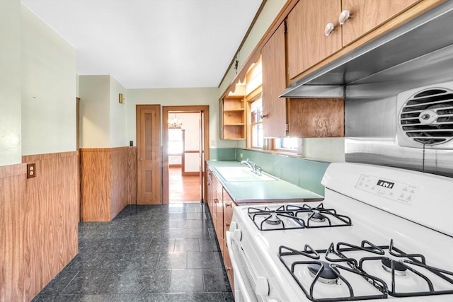 kitchen featuring white range with gas cooktop, a wainscoted wall, light countertops, open shelves, and a sink