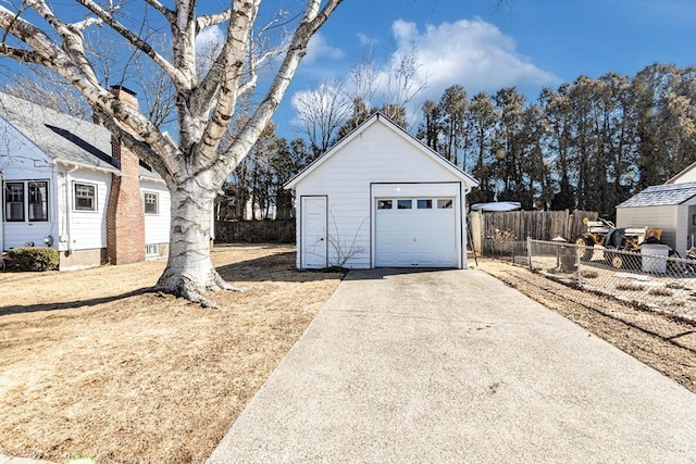 detached garage with fence and concrete driveway