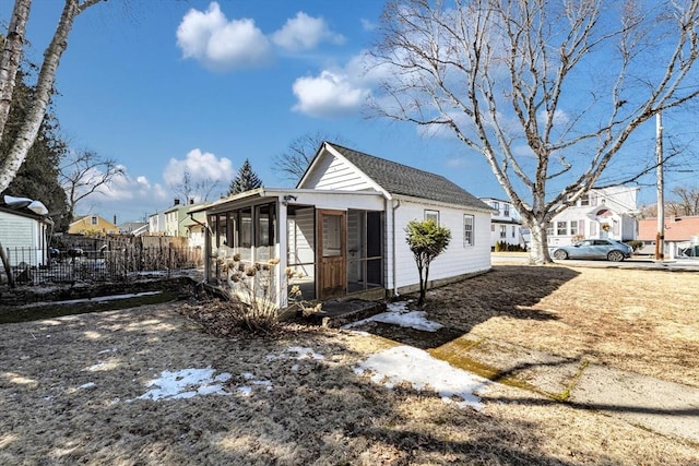 view of side of home featuring a residential view, a sunroom, and fence