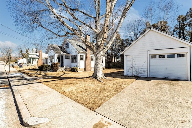 exterior space featuring a detached garage, a residential view, concrete driveway, and an outbuilding