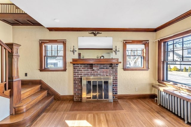 living room with radiator heating unit, stairway, wood finished floors, and ornamental molding