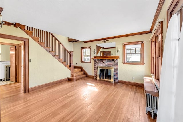 unfurnished living room with a fireplace, wood finished floors, baseboards, stairs, and radiator heating unit