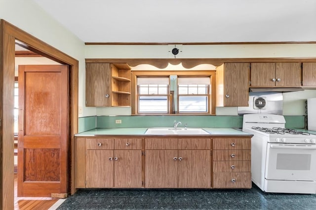 kitchen with light countertops, gas range gas stove, a sink, and brown cabinetry