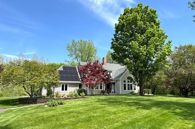 187 Plain Rd, Greenfield, MA 01301 - view of property hidden behind natural elements with roof mounted solar panels, a front yard, and a chimney