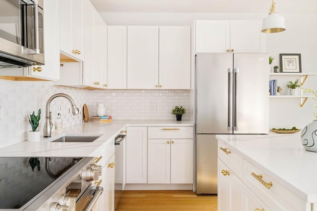 kitchen with white cabinetry, stainless steel appliances, decorative light fixtures, and sink